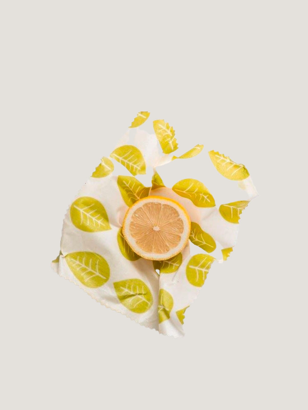 en halv citron i bivokspapir med motiv af blade